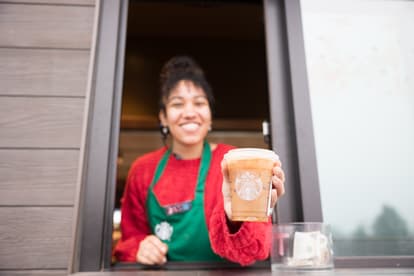 Morning Joe at Starbucks. Young woman handing a coffee beverage out the drive through window 